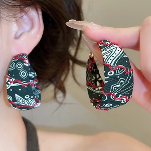 Vue détaillée de créoles bohèmes en tissu imprimé avec bordure rouge et motifs tribaux chic