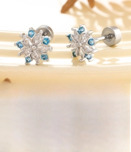 Macro shot of silver snowflake ear stud featuring blue and white cubic zirconia stones