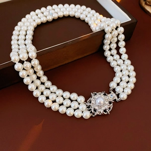 Detail of vintage silver flower clasp on a three-layer pearl necklace with elegant gloss
