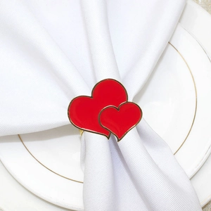 Detail of red heart-shaped napkin ring with gold trim on white cloth for table decor