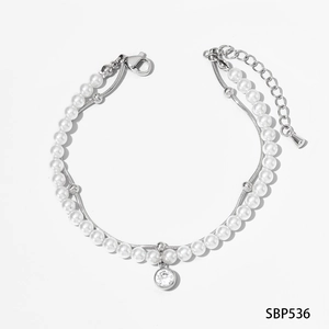 Détail du bracelet double couche avec perles blanches, chaîne serpent et pendentif en zircon