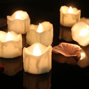 Atmospheric warm LED tear-drip candles on reflective surface with dried petals