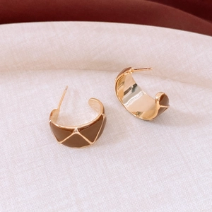 Detail of vintage 18k gold C-shape earrings with dark brown geometric enamel patterns