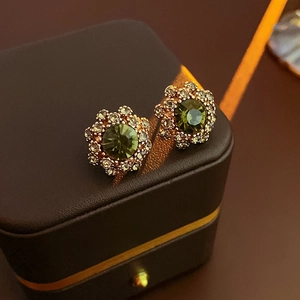 Detail view of flower earrings with green gemstone and rose gold plating in a gift box