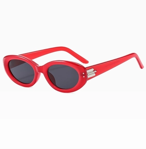 Detail of red oval sunglasses with silver triple stripe metal trim and dark lenses