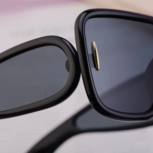 Macro shot of stylish black cycling sunglasses showing gold metal hardware and lens detail
