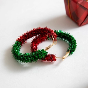 Detailed view of red and green tinsel wreath earrings for Christmas with festive gift box