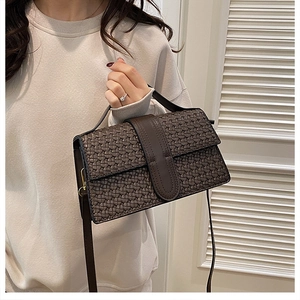 Detail of dark brown woven textured crossbody bag featuring gold hardware and top handle