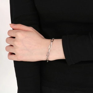Close-up of a silver stainless steel square-wire chain bracelet on a wrist with black sleeve