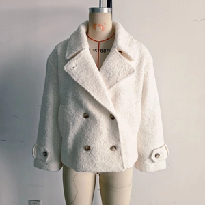 Detail of white bouclé coat featuring double-breasted buttons and lapel collar
