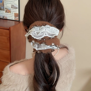 Close-up of brown knit scrunchie with layered white lace trim worn on a ponytail