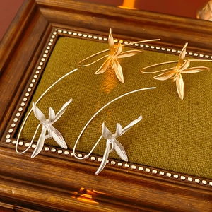 Detailed view of iris flower earrings in gold and silver finish on a green velvet tray