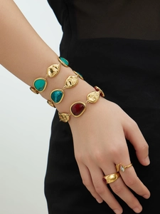 Detail of 18K gold plated stainless steel bracelets and rings with resin gemstone inlays