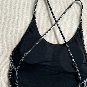 Close-up of black backless swimsuit with silver snake-pattern straps and cross-back design