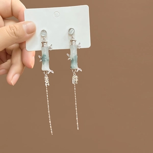 Detail of silver bamboo earrings with light green tassels and Chinese lucky charms
