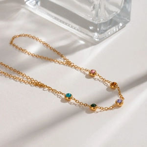 Detail of gold finger chain bracelet featuring five vibrant round colored gemstones