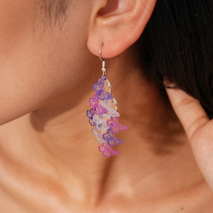 Detailed view of long tiered purple butterfly earrings with hollow wings on model