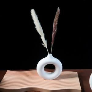 Dettaglio del vaso donut in ceramica bianca opaca con pampa su base in legno ondulato