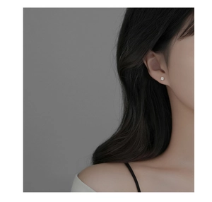Close-up of minimalist S999 sterling silver rose stud earring worn on a female ear lobe
