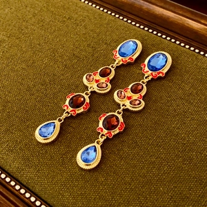 Detail of vintage palace style drop earrings with blue stones and red enamel tassels