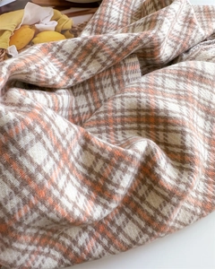 Macro shot of plaid scarf fabric showing soft cashmere-like texture and orange-brown stripes