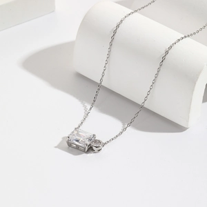 Detail of silver geometric necklace featuring a baguette and round-cut zirconia pendant