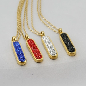 Détail de quatre pendentifs rectangulaires dorés sertis de strass colorés sur colliers
