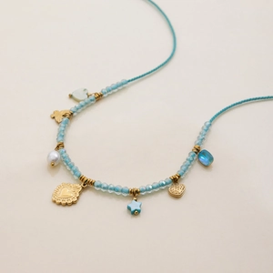 Blue beaded necklace with gold heart pendants and pearl detail for women on beige backdrop