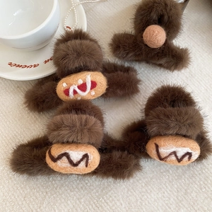 Detailed view of four brown plush hair claws with wool felt patches on white fabric
