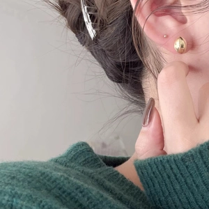 Minimalist S925 sterling silver bean-shaped gold studs worn on ear with green knitwear