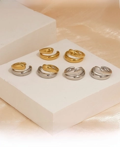Polished 316 stainless steel hoop earrings in gold and silver on a silk background