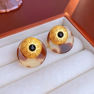 Macro view of vintage gold stud earrings with black gemstone and amber resin base