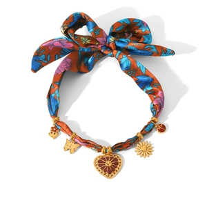 Collier en tissu floral avec nœud et pendentifs cœur dorés sur fond blanc
