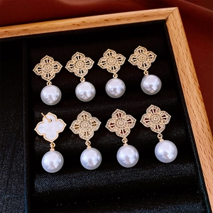 Detail of multiple hollow flower earrings with white pearls on a black velvet tray