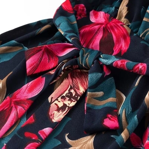Detail of waist tie-up knot on deep blue dress with vibrant red floral print fabric