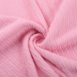 Détail de la texture du tissu plissé rose avec plis verticaux et finition soyeuse