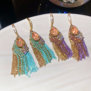 Macro shot of tassel earrings featuring pink teardrop stones and colorful crystal chains