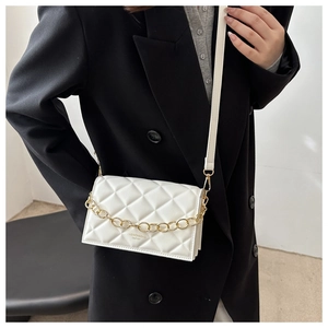 Detail shot of white quilted crossbody bag with gold chain and fashion lettering on cover