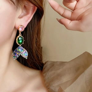 Gros plan détaillé de boucles d'oreilles queue de poisson avec gemmes roses sur modèle