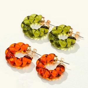 Macro shot of translucent olive green and amber orange twisted resin hoop earrings