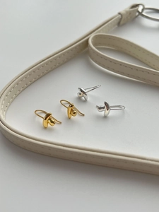 Detailed view of minimalist fluid gold and silver drop earrings on a soft textured base
