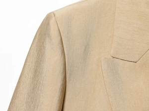 Detailopname van de champagne goud zijden stoftextuur en stiksels op de luxe blazer