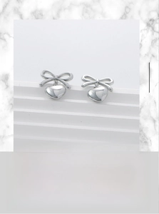 Detailed view of polished 18K gold-plated stainless steel bow and heart stud earrings