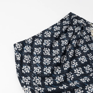 Détail du tissu floral bleu marine avec plis élégants et perles délicates