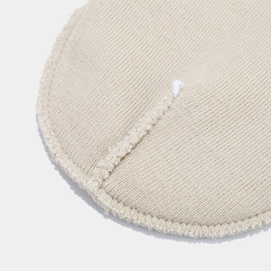 Detailed close-up of beige ribbed knit fabric with seamless stitching on a beanie hat