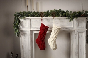 Classic red and cream knit Christmas stockings with cable patterns hanging on a fireplace