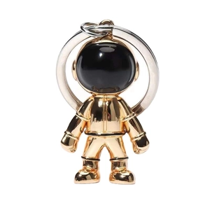 Golden astronaut keychain in polished metal alloy with black helmet visor on white backdrop