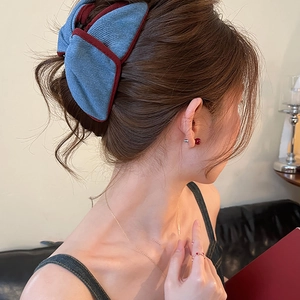 Chic blue corduroy bow hair claw with red edges worn by a model in a cozy setting