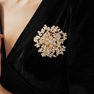 Detail of handmade flower brooch with white pearls on black velvet fabric