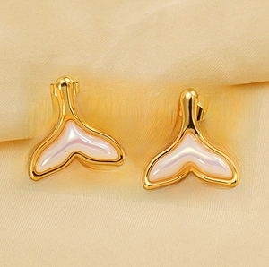 Detailed view of gold fishtail stud earrings with iridescent shell inlay on silk fabric